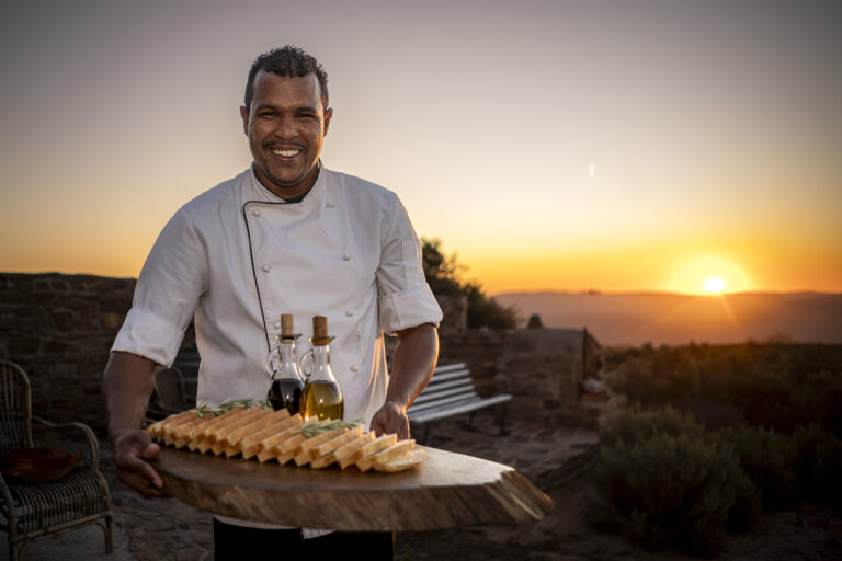 Chef displaying a platter outside at sunset