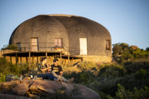 2 people having a picnic on a rock in front of a mountain suite